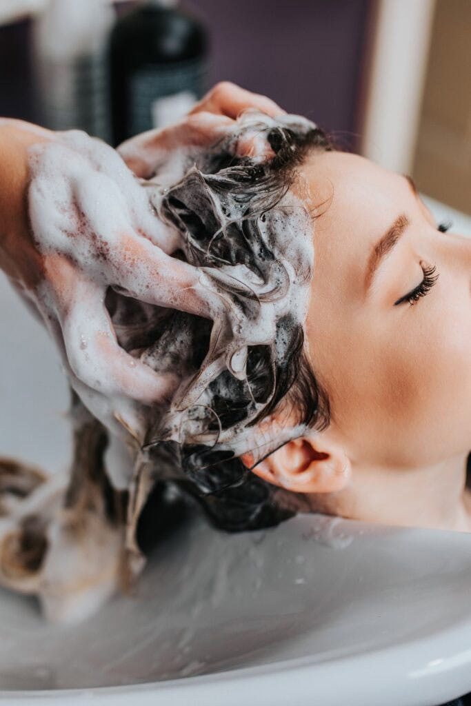 Professioneller Friseur wäscht die Haare einer schönen jungen Frau